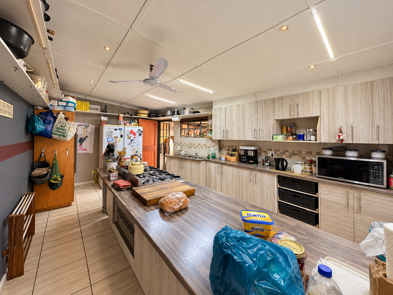 Spacious kitchen featuring extensive built-in cabinetry, a large central island with a gas hob, and tiled flooring throughout.