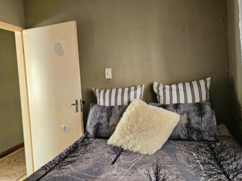A compact bedroom featuring neutral wall tones and a standard internal door, offering a functional space ready for cosmetic updates.