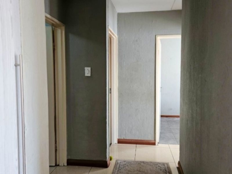 A functional apartment hallway featuring tiled flooring and neutral grey walls, providing access to multiple rooms within the unit.