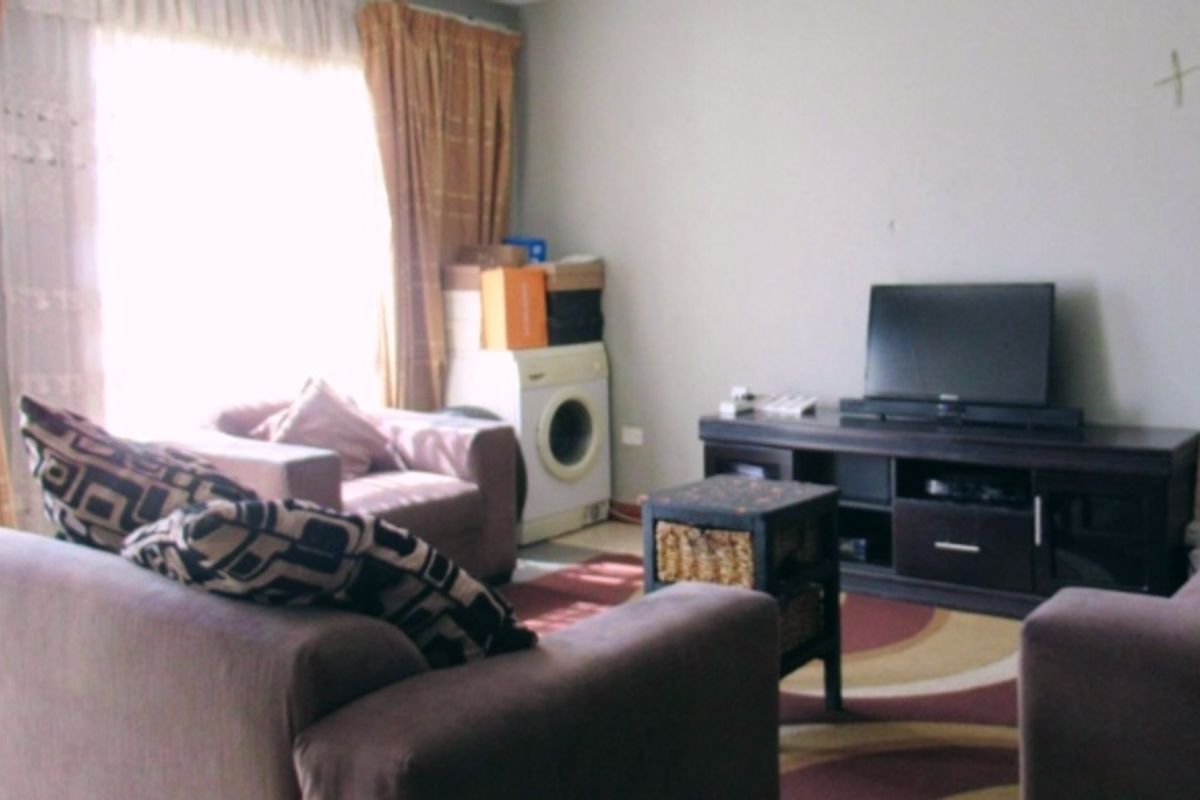 A living room area featuring a large window with curtains, providing natural light to the space.