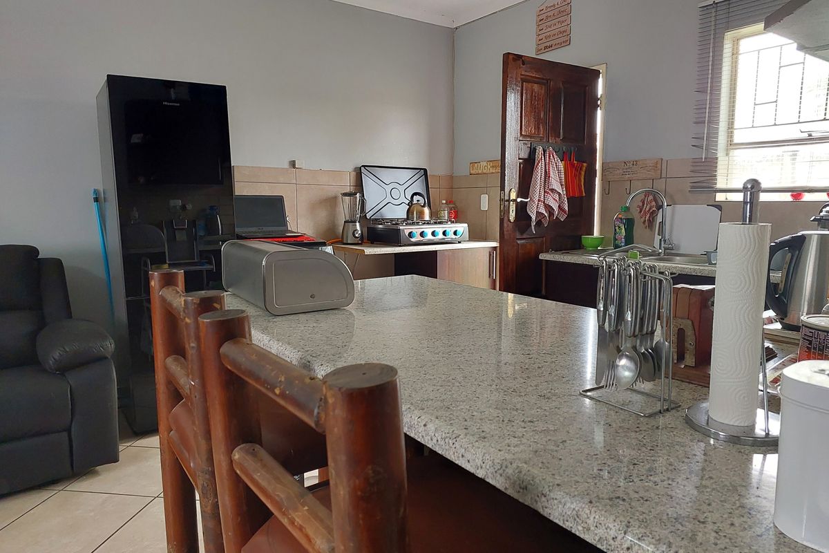 A functional kitchen featuring a granite-topped island, tiled backsplash, and ceramic flooring, providing a practical workspace for daily meal preparation.