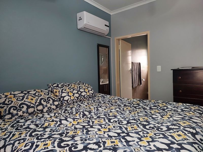 A well-maintained bedroom featuring a wall-mounted split-system air conditioner and direct access to an adjoining bathroom.