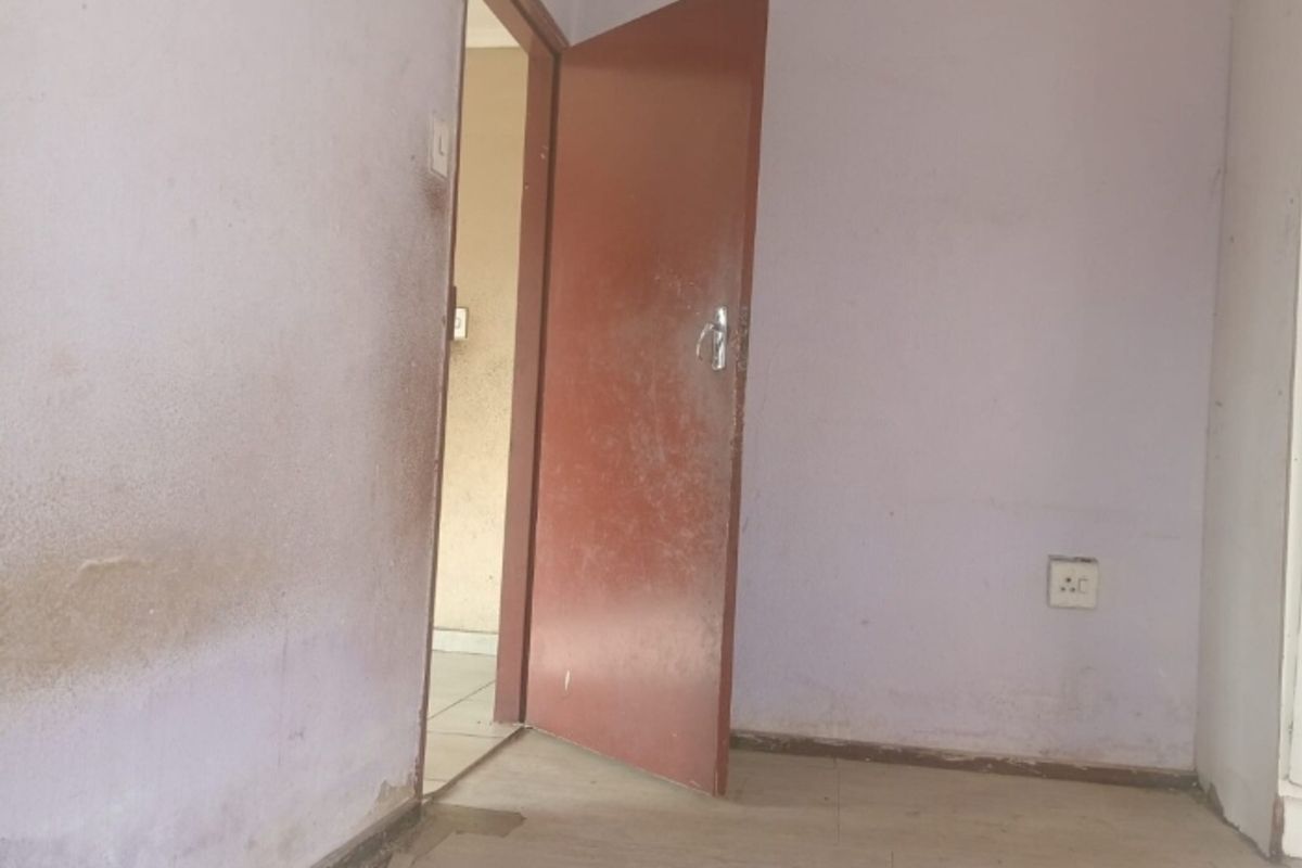 An empty bedroom interior featuring plain walls and a standard internal door, requiring cosmetic updates and fresh paint to improve its overall condition.