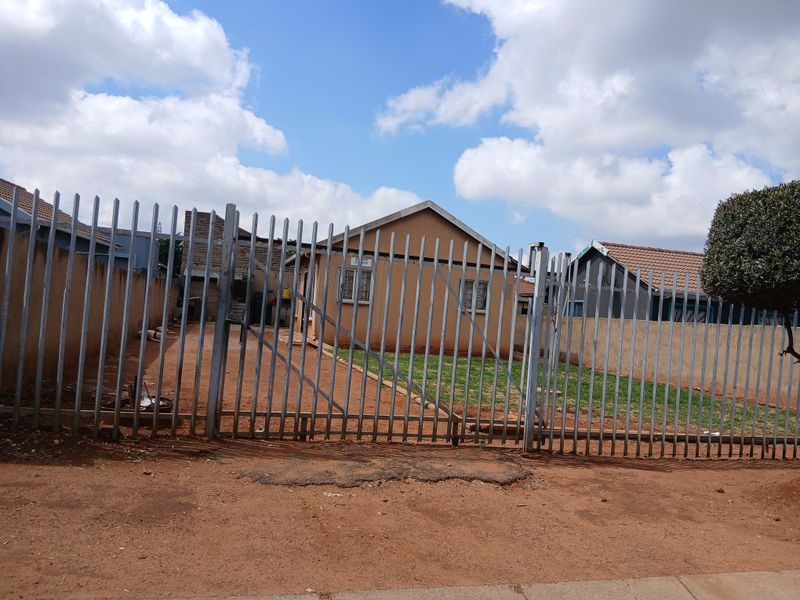 Front view of a residential property featuring a secure steel palisade fence, gated entrance, and a tiled roof structure.