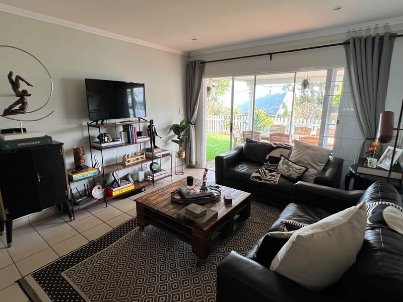 A comfortable living room featuring tiled flooring and large sliding glass doors that provide natural light and access to the outdoor patio area.