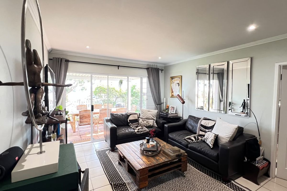 A bright living room featuring tiled flooring, recessed downlighting, and large sliding glass doors that provide direct access to the outdoor patio area.