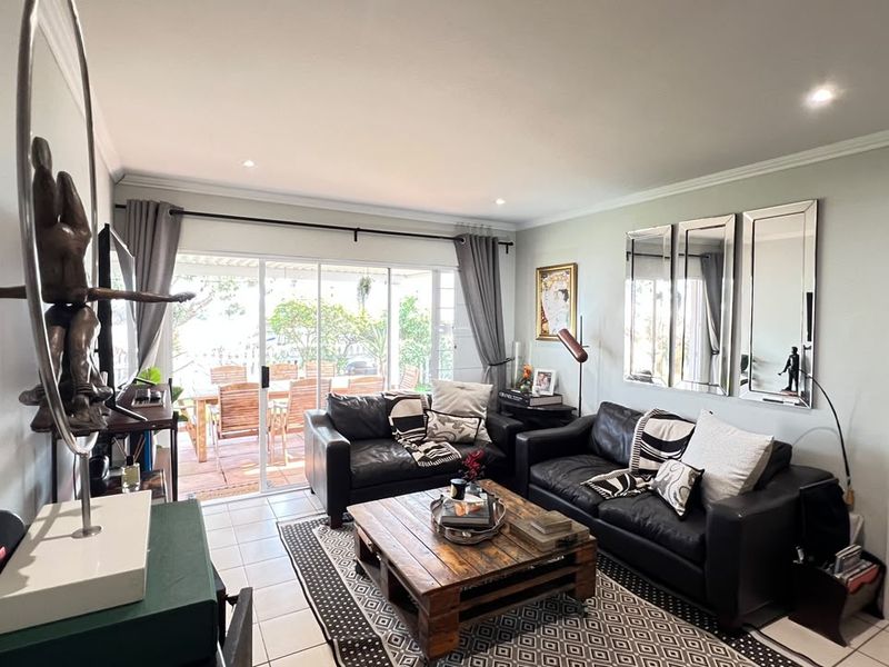 A bright living room featuring tiled flooring, recessed downlighting, and large sliding glass doors that provide direct access to the outdoor patio area.