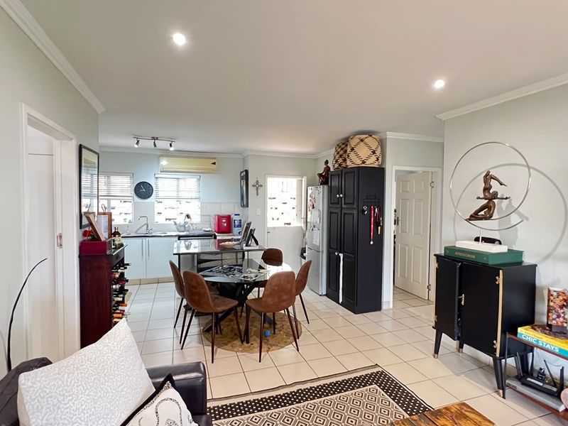 Open plan living and dining area featuring tiled flooring, recessed lighting, and a functional kitchen with built-in cabinetry and storage.