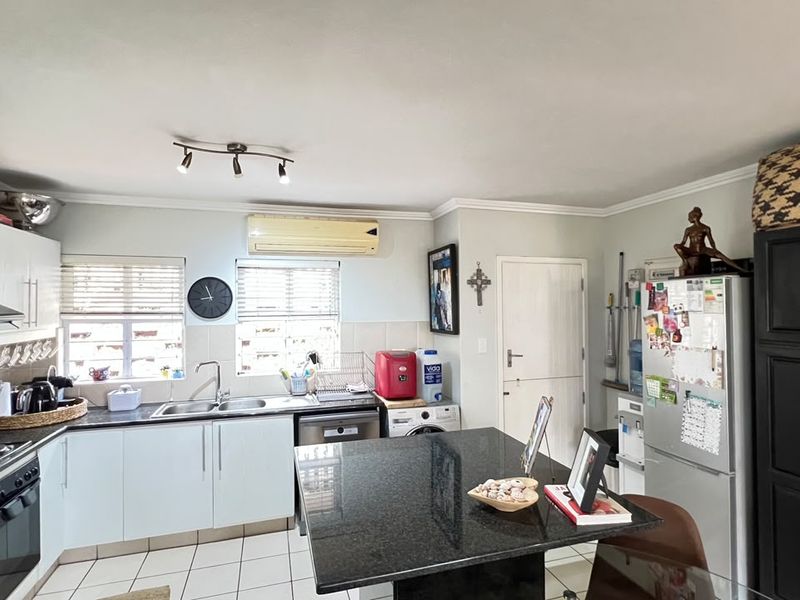 Functional kitchen featuring granite countertops, built-in oven, extractor fan, and tiled flooring, offering a practical layout for daily meal preparation.