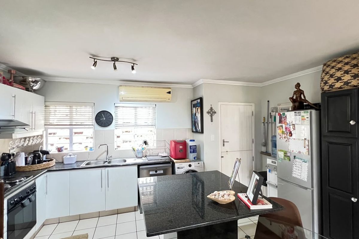 Functional kitchen featuring granite countertops, built-in oven, extractor fan, and tiled flooring, offering a practical layout for daily meal preparation.