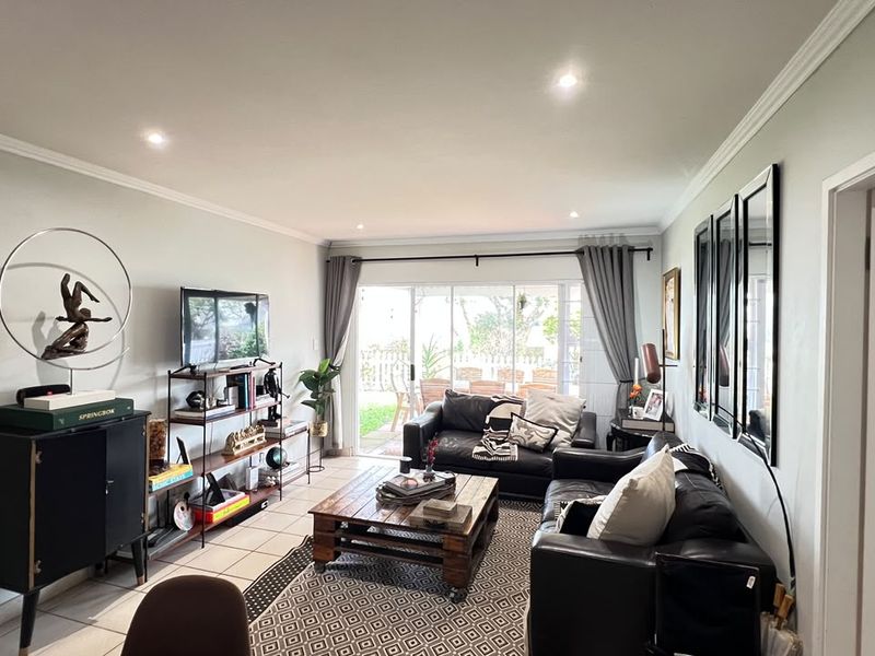 A well-lit living room featuring tiled flooring, crown molding, and large sliding glass doors that provide direct access to the outdoor area.