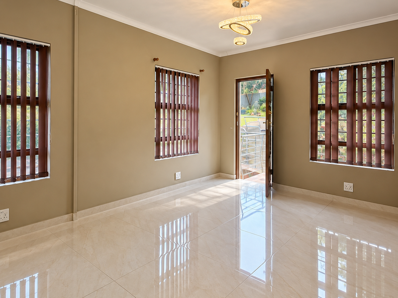 A bright, empty living room featuring polished porcelain floor tiles, modern lighting, and large windows with vertical blinds, offering direct access to the exterior.