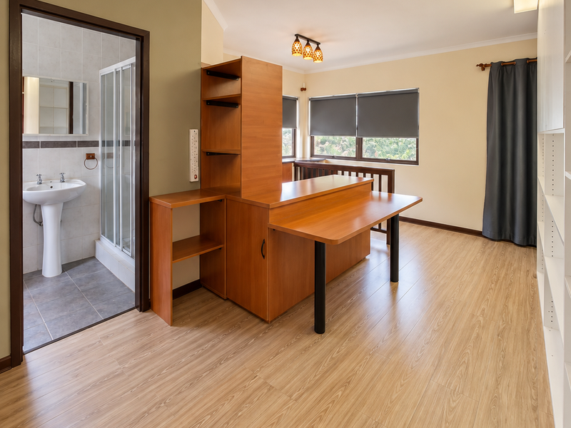 A bedroom featuring laminate flooring, built-in storage units, and an adjoining en-suite bathroom with a pedestal basin and shower enclosure.