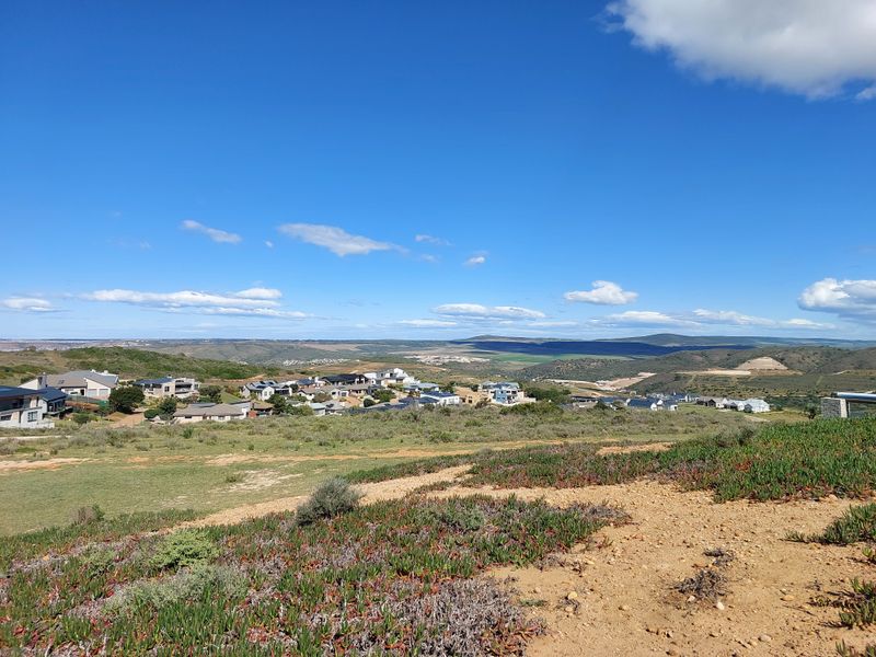 A scenic elevated view overlooking a residential estate and surrounding natural landscape under a clear blue sky.