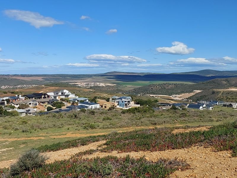 A scenic elevated view overlooking a residential estate nestled within a natural landscape with rolling hills in the distance.