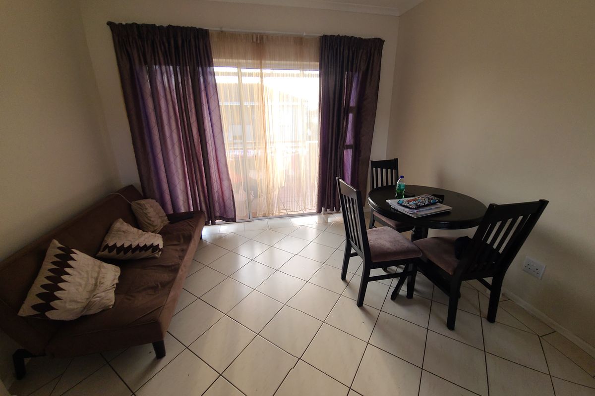 A living area featuring tiled flooring and a large sliding glass door that provides access to an outdoor space.