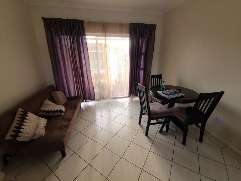 A living area featuring tiled flooring and a large sliding glass door that provides access to an outdoor space.