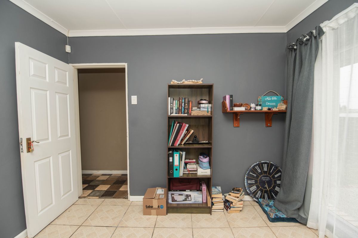 A bedroom featuring tiled flooring, dark grey painted walls, and a coved ceiling, providing a neutral base for interior design updates.