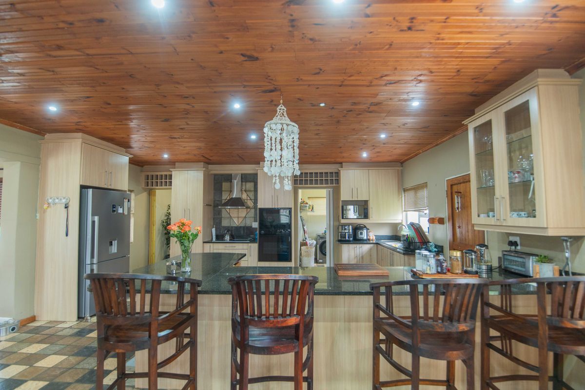 Spacious kitchen featuring a large granite-topped island, timber ceiling, and ample built-in cabinetry with integrated appliances.