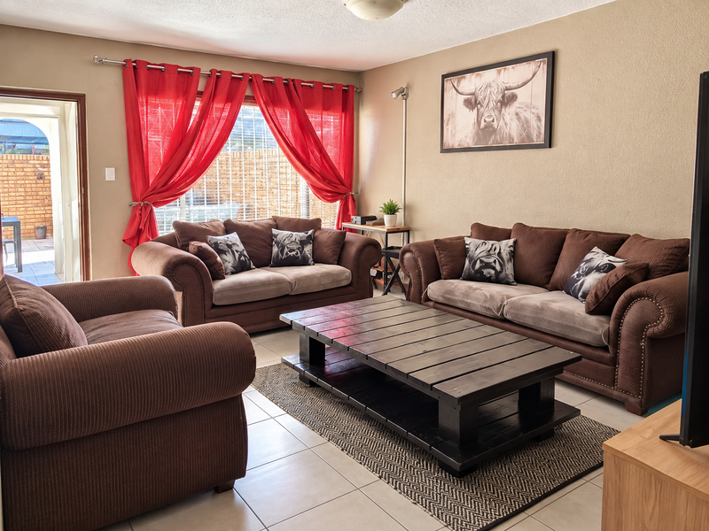 A comfortable living room featuring tiled flooring and natural light, with direct access to an outdoor patio area.