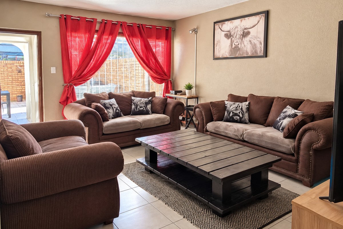 A comfortable living room featuring tiled flooring and natural light, with direct access to an outdoor patio area.