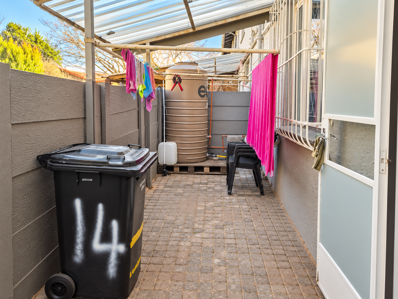 A functional outdoor utility area featuring a water storage tank, paved flooring, and a covered structure, providing practical space for household maintenance.