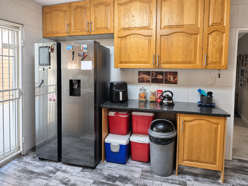 A functional kitchen area featuring wooden cabinetry, granite countertops, and tiled finishes, providing practical storage and workspace.