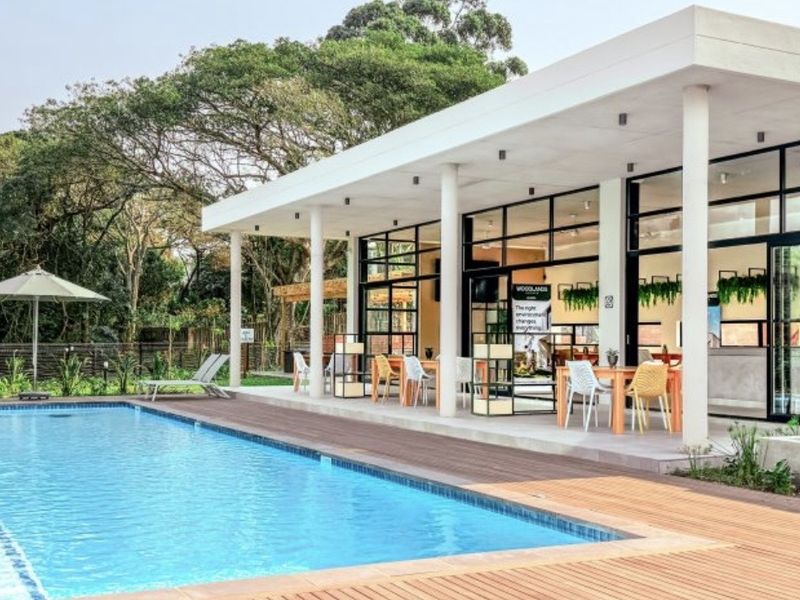 A modern outdoor entertainment area featuring a swimming pool, timber decking, and a spacious covered patio with large glass doors.