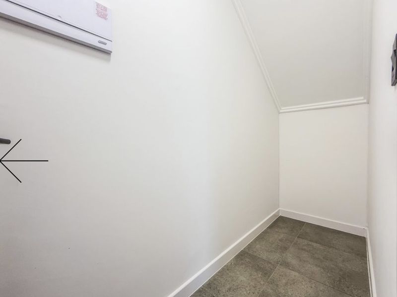A clean, empty utility space featuring tiled flooring, coving, and a wall-mounted split-system air conditioning unit.