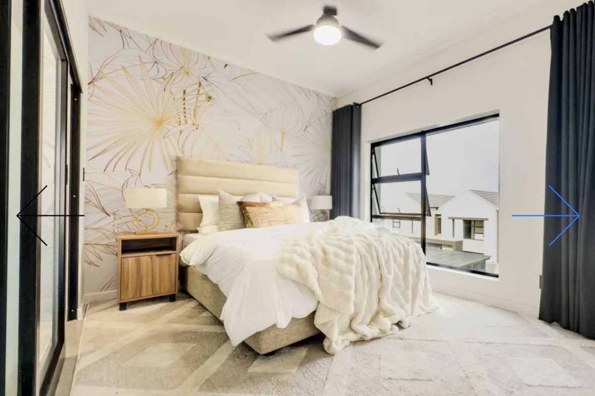 A well-lit bedroom featuring a modern ceiling fan, large aluminium-framed windows, and decorative feature wallpaper.