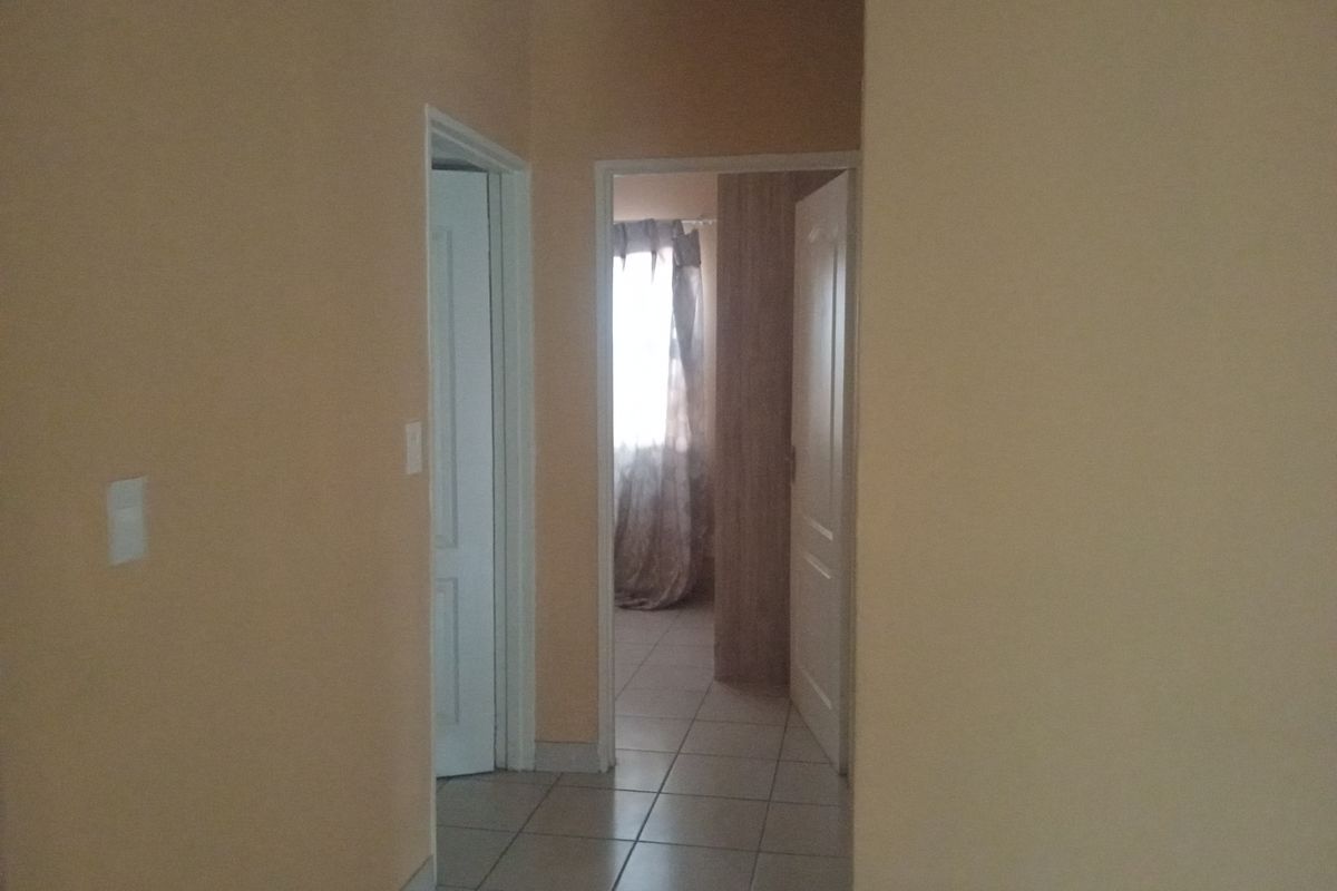 A functional hallway with tiled flooring connecting multiple rooms, featuring neutral wall tones and standard internal door frames.