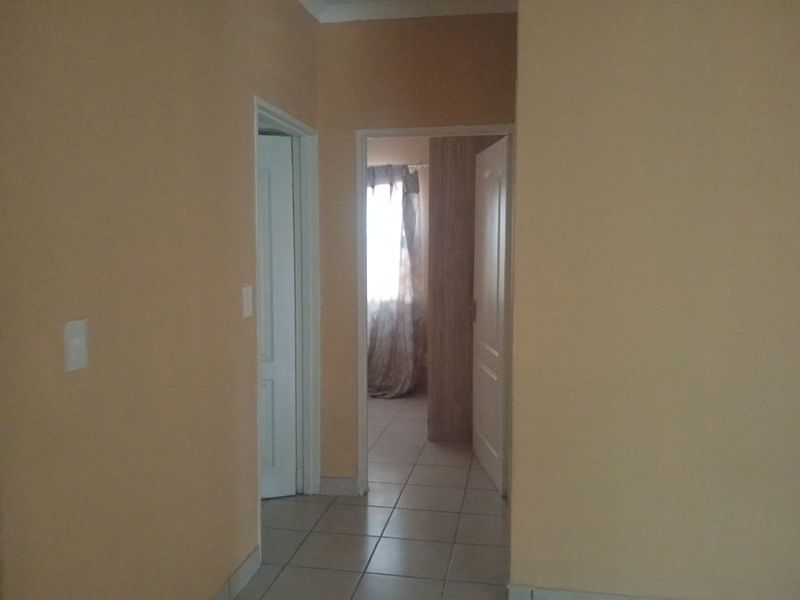 A functional hallway with tiled flooring connecting multiple rooms, featuring neutral wall tones and standard internal door frames.