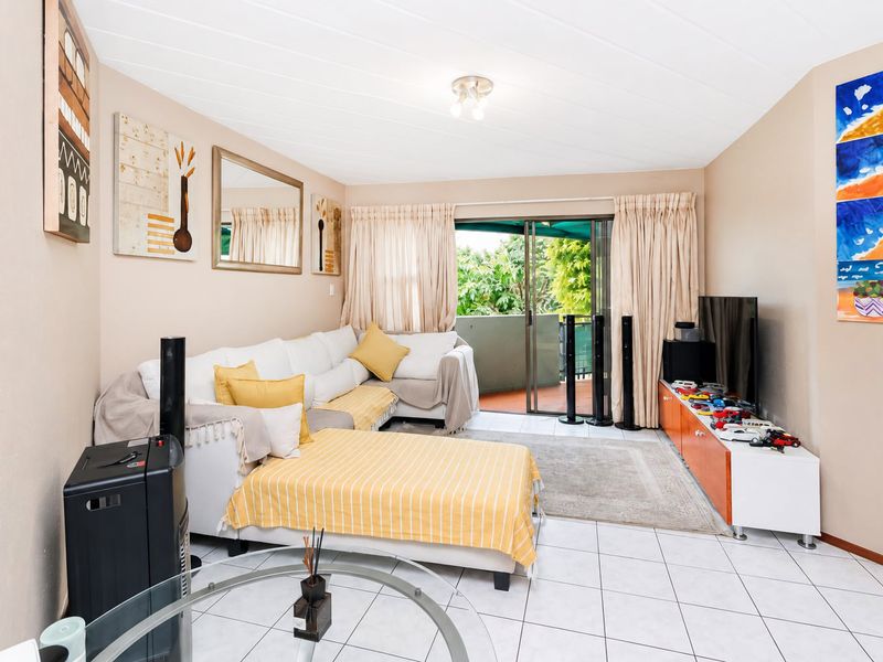 A living room featuring tiled flooring, a tongue and groove ceiling, and a sliding glass door providing access to an outdoor balcony area.