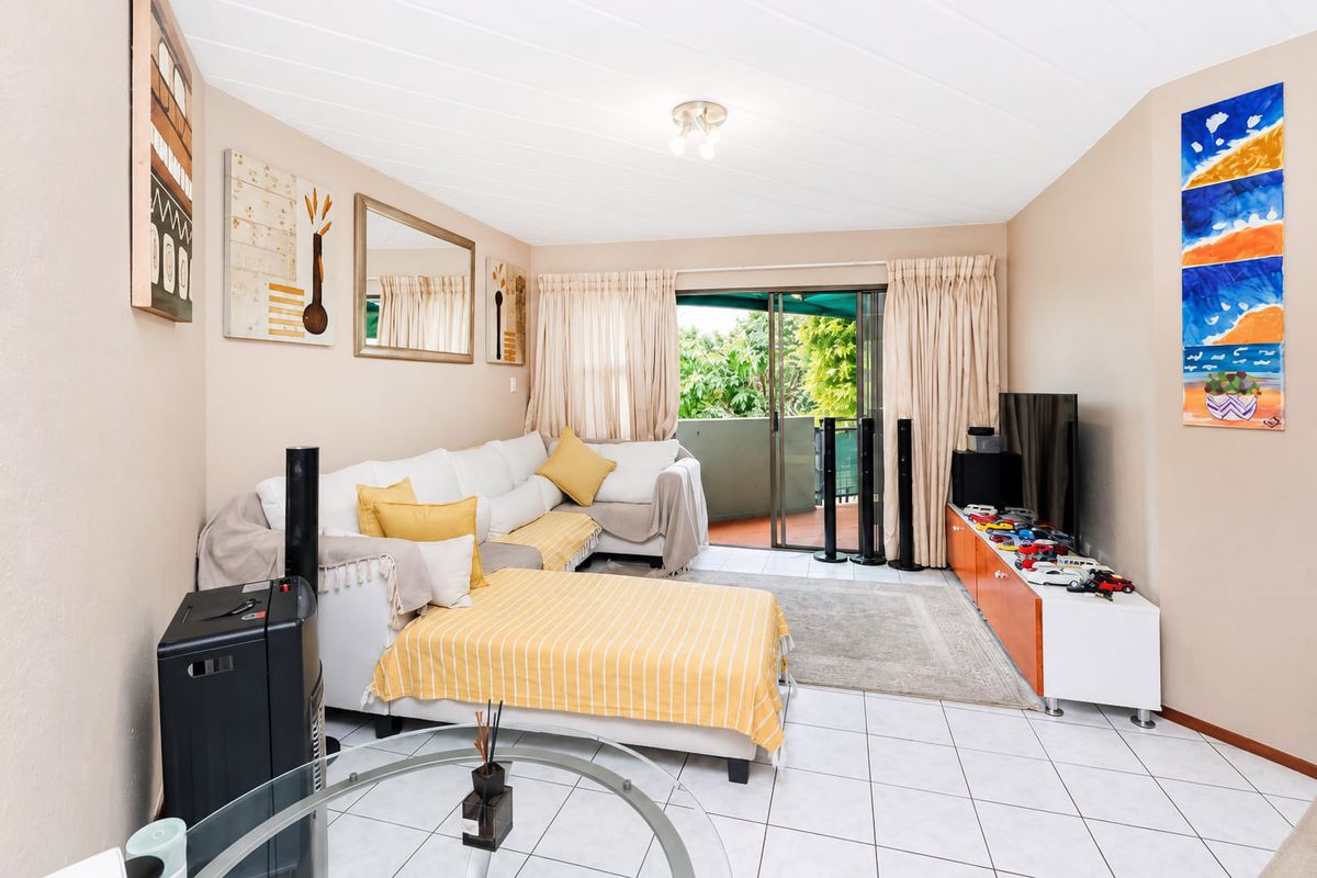A living room featuring tiled flooring, a tongue and groove ceiling, and a sliding glass door providing access to an outdoor balcony area.