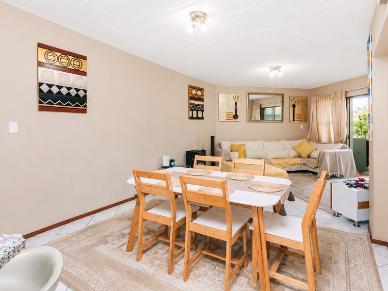 An open-plan living and dining area featuring tiled flooring and a sliding glass door leading to an outdoor space.