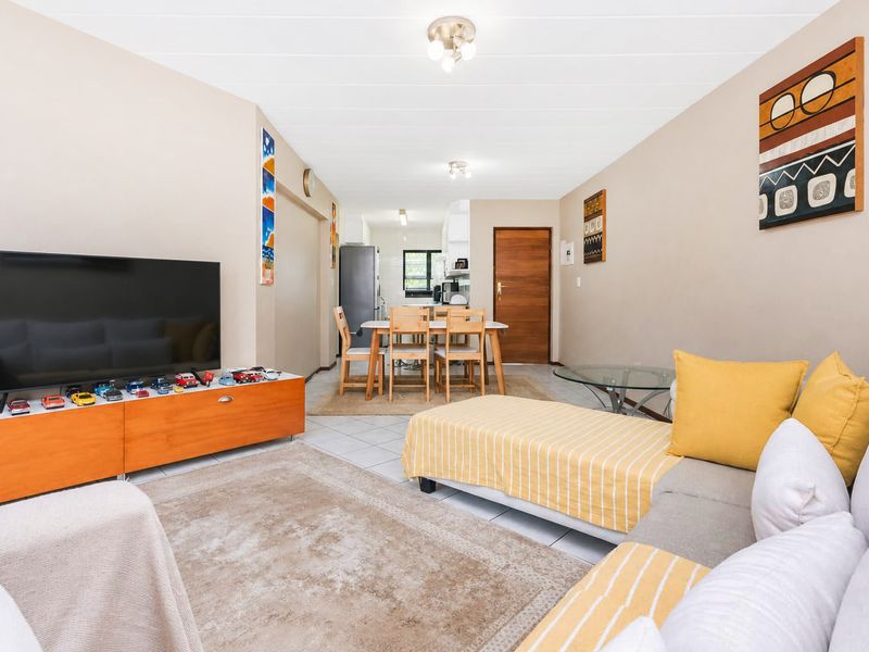 Open-plan living and dining area featuring neutral wall tones, tiled flooring, and direct access to the kitchen space.
