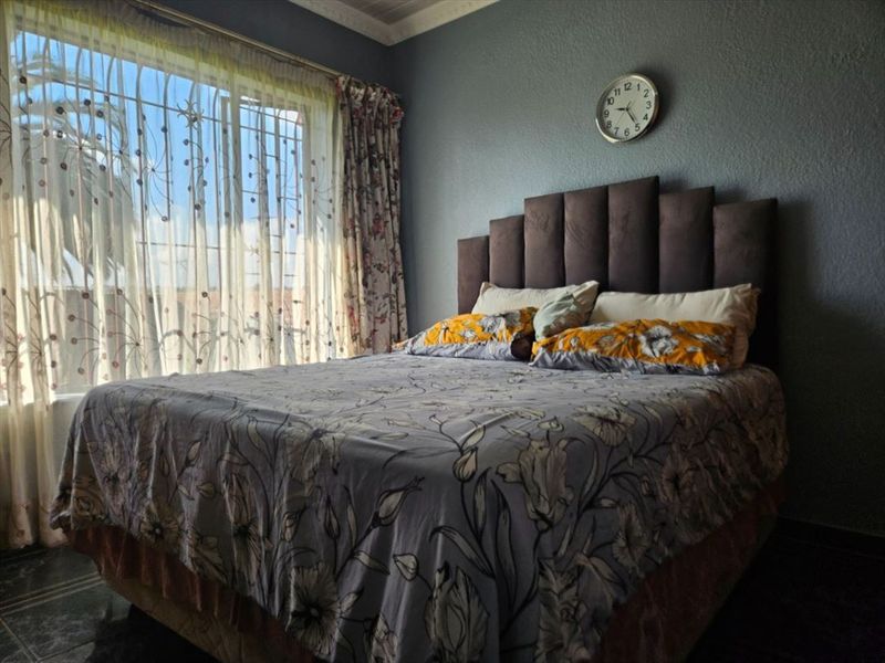 A bedroom featuring crown molding and a large window with security bars, providing natural light.