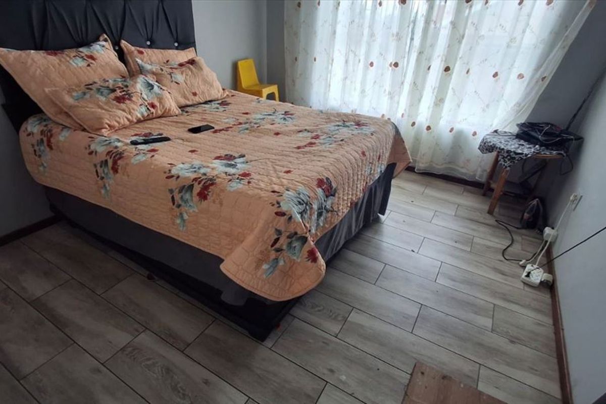 A bedroom featuring wood-look tile flooring and neutral wall finishes, providing a functional space with natural light from the window.