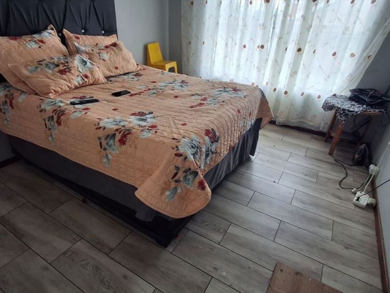 A bedroom featuring wood-look tile flooring and neutral wall finishes, providing a functional space with natural light from the window.