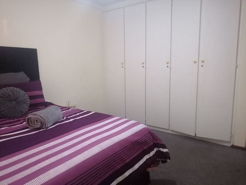 A bedroom featuring wall-to-wall built-in cupboards and carpeted flooring.