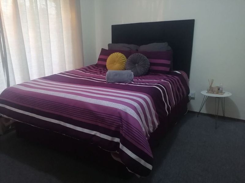 A standard bedroom featuring carpeted flooring and window treatments, providing a functional and private sleeping space.