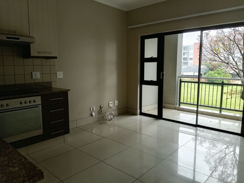 Open plan kitchen and living area featuring tiled floors, granite countertops, built-in oven, and direct access to a private balcony through sliding glass doors.