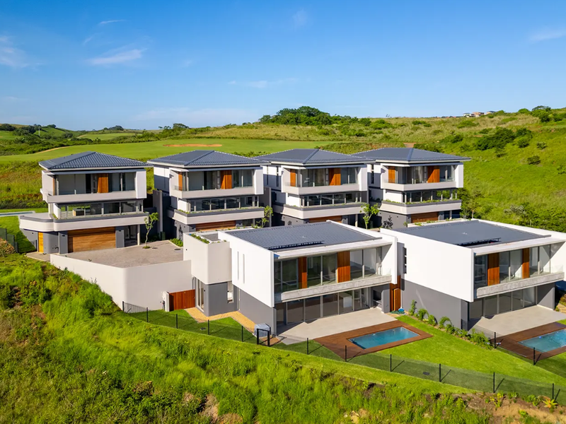 Aerial view of a modern residential complex featuring multiple multi-story homes with private swimming pools, timber decks, and landscaped surroundings.