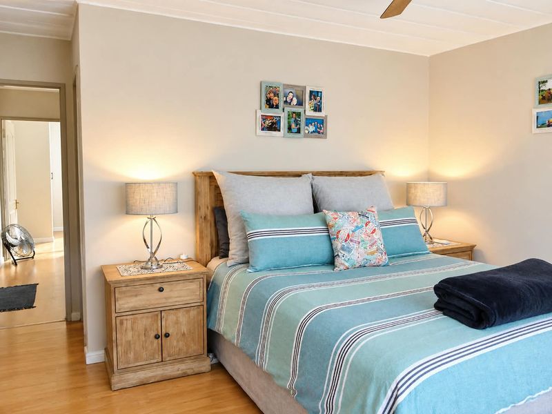 A well-maintained bedroom featuring hardwood flooring and a ceiling fan, offering a comfortable and neutral living space.