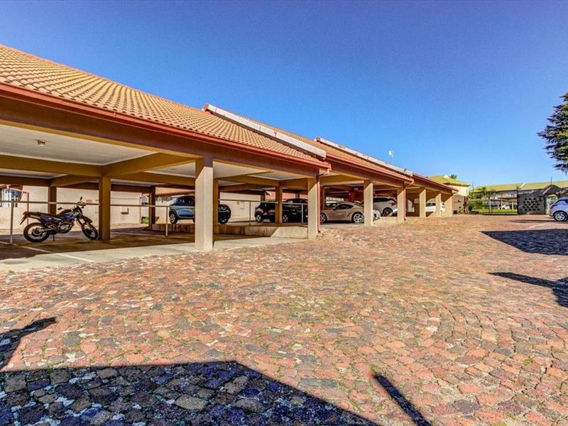 A well-maintained outdoor parking area featuring multiple covered bays with concrete pillars and durable cobblestone paving.