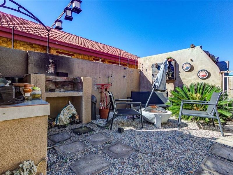 Outdoor patio area featuring a built-in braai, gravel ground cover, and perimeter boundary walls, suitable for outdoor entertaining.