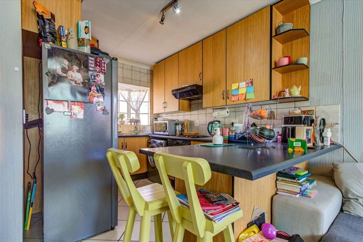 A functional kitchen featuring laminate cabinetry, a breakfast bar, tiled backsplash, and tiled flooring, offering a practical layout for daily use.