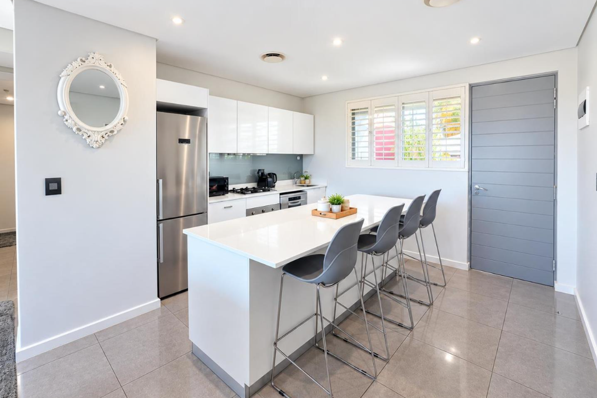 Modern kitchen featuring a central island with breakfast bar seating, sleek white cabinetry, quartz countertops, and high-quality stainless steel appliances.