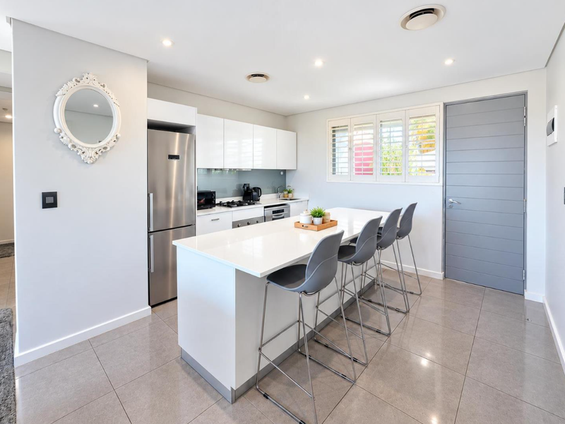 Modern kitchen featuring a central island with breakfast bar seating, sleek white cabinetry, quartz countertops, and high-quality stainless steel appliances.