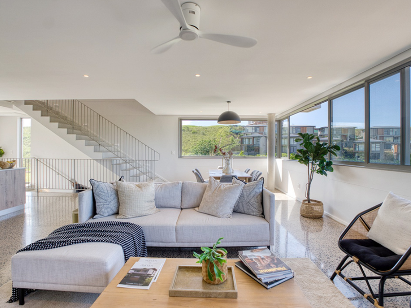 Spacious open-plan living area featuring modern terrazzo flooring, a sleek staircase with metal balustrade, and large windows offering natural light and scenic views.